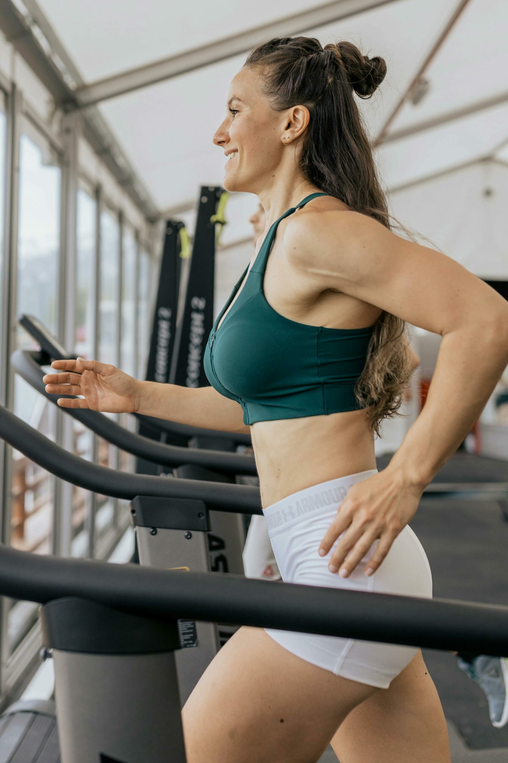 Fit woman jogging on treadmill in an airy gym, focused on health and fitness.