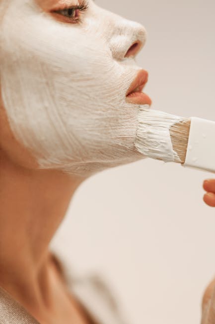 pexels-photo-12008270-12008270 Detailed shot of a woman applying a white face mask with a brush, highlighting skincare routine.