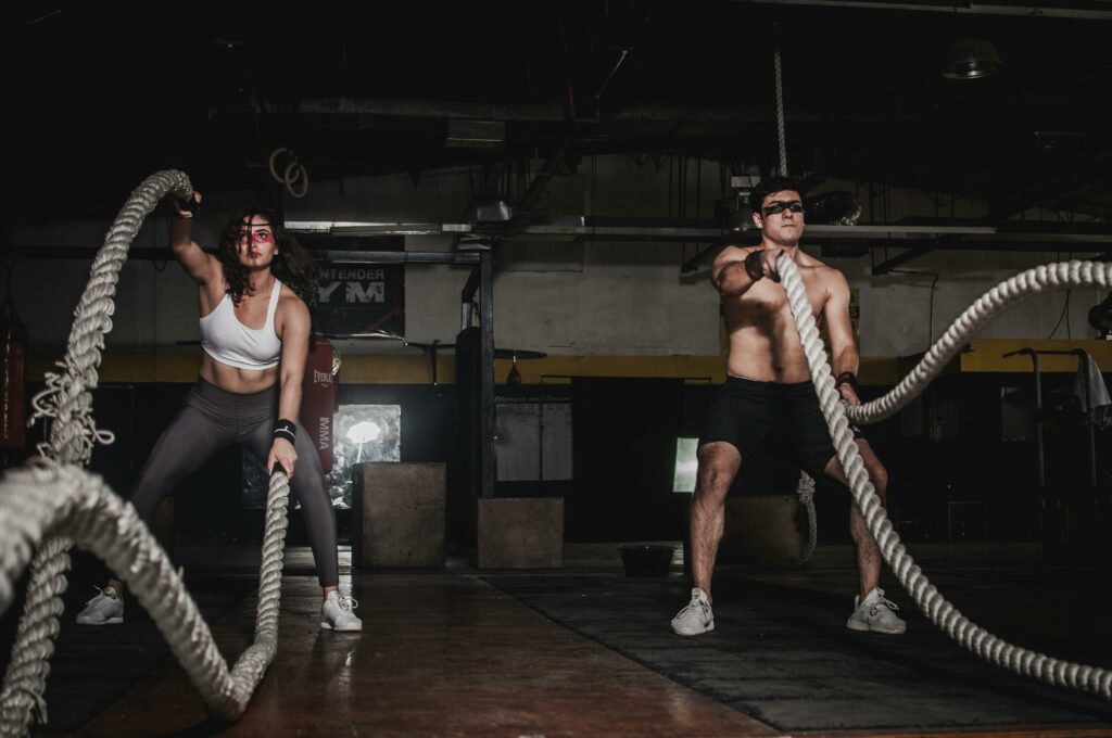 pexels-photo-1552242-1552242 Two people engage in a powerful indoor battle rope workout, showcasing strength and energy.