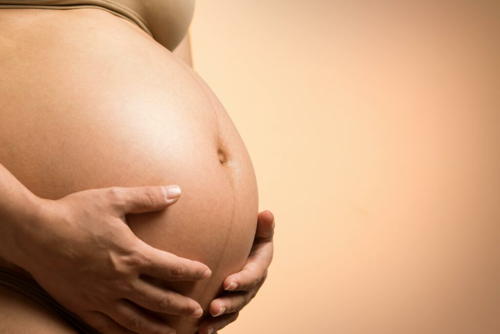 pexels-photo-1556669-1556669 A tender close-up of a pregnant woman's hands holding her belly, symbolizing maternity and love.