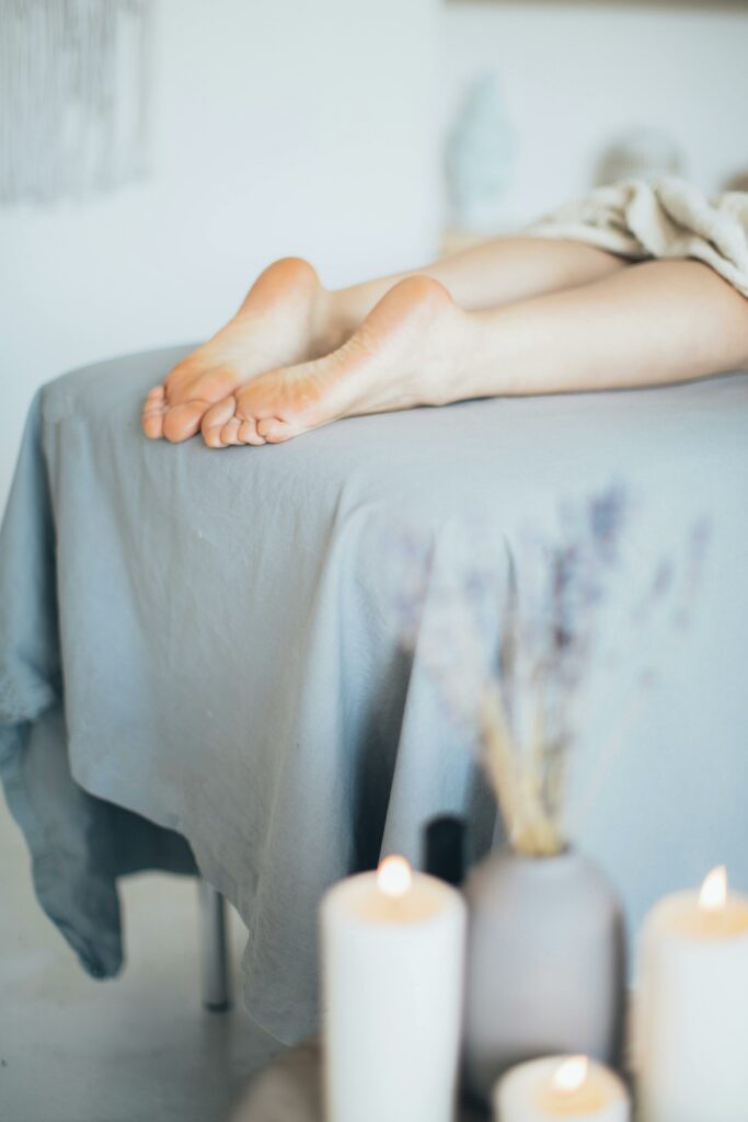 pexels-photo-3865588-3865588 A peaceful spa setting featuring candles and bare feet on a massage table, perfect for relaxation themes.